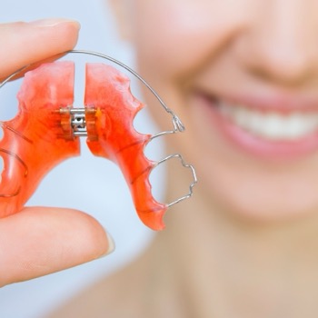 Retainer held in front of a smiling patient